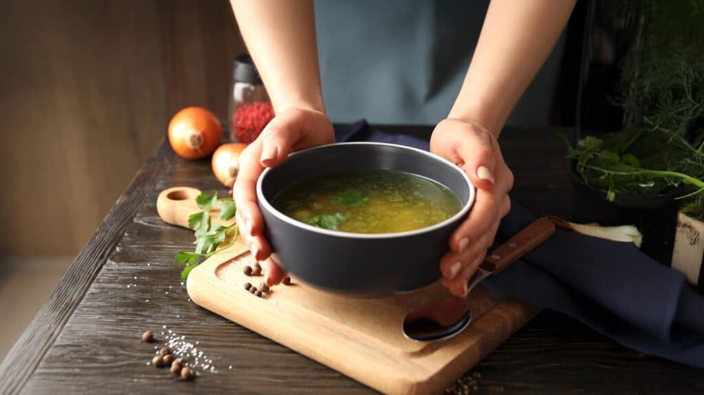 Eine Person hält eine Suppenschüssel mit veganer Suppe mit Umami vegan